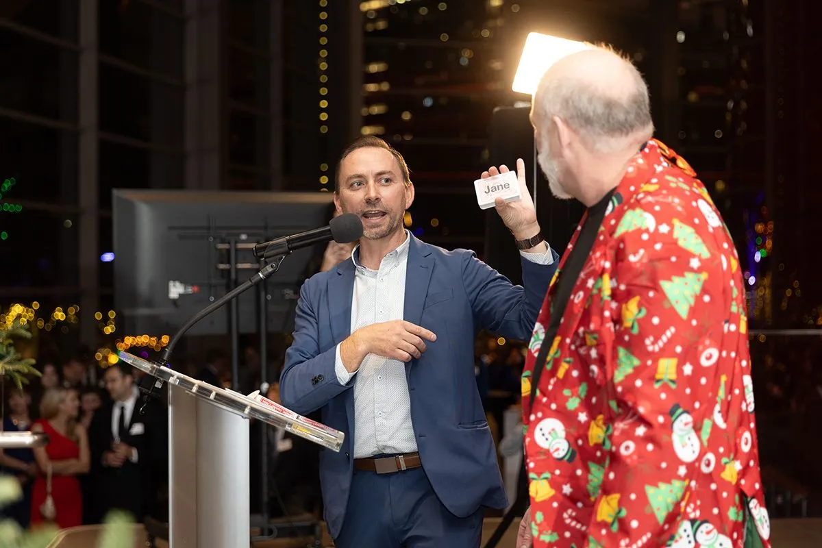 Brian on stage with a volunteer holding up a name card